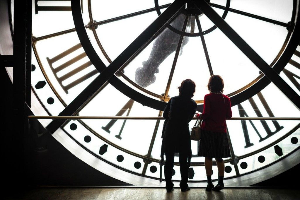 Zwei Menschen vor einer riesigen Uhr im Inneren eines Turms.